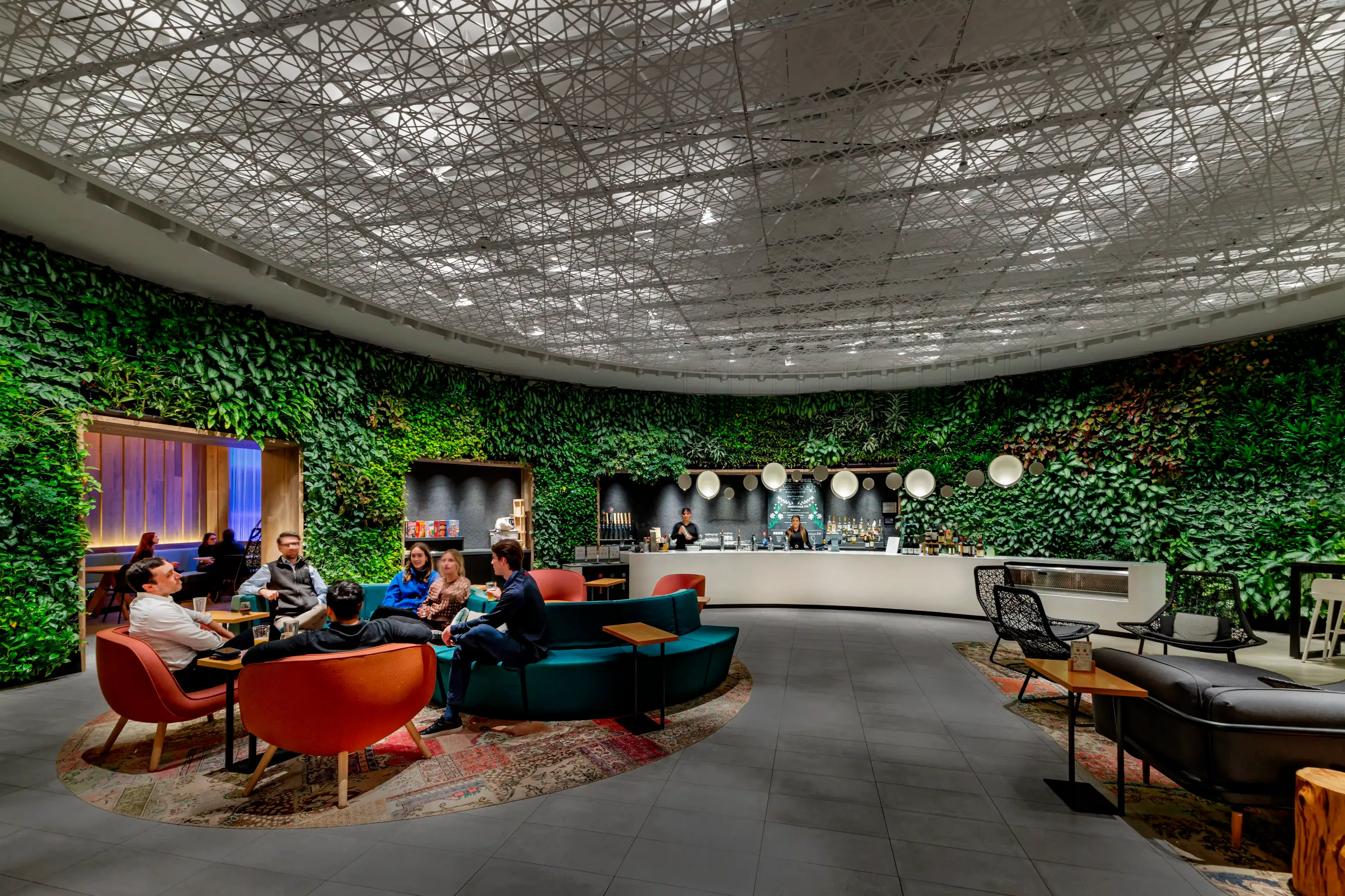 A lounge area with bar adorned with lush green plants growing on the walls, creating a refreshing and natural ambiance.