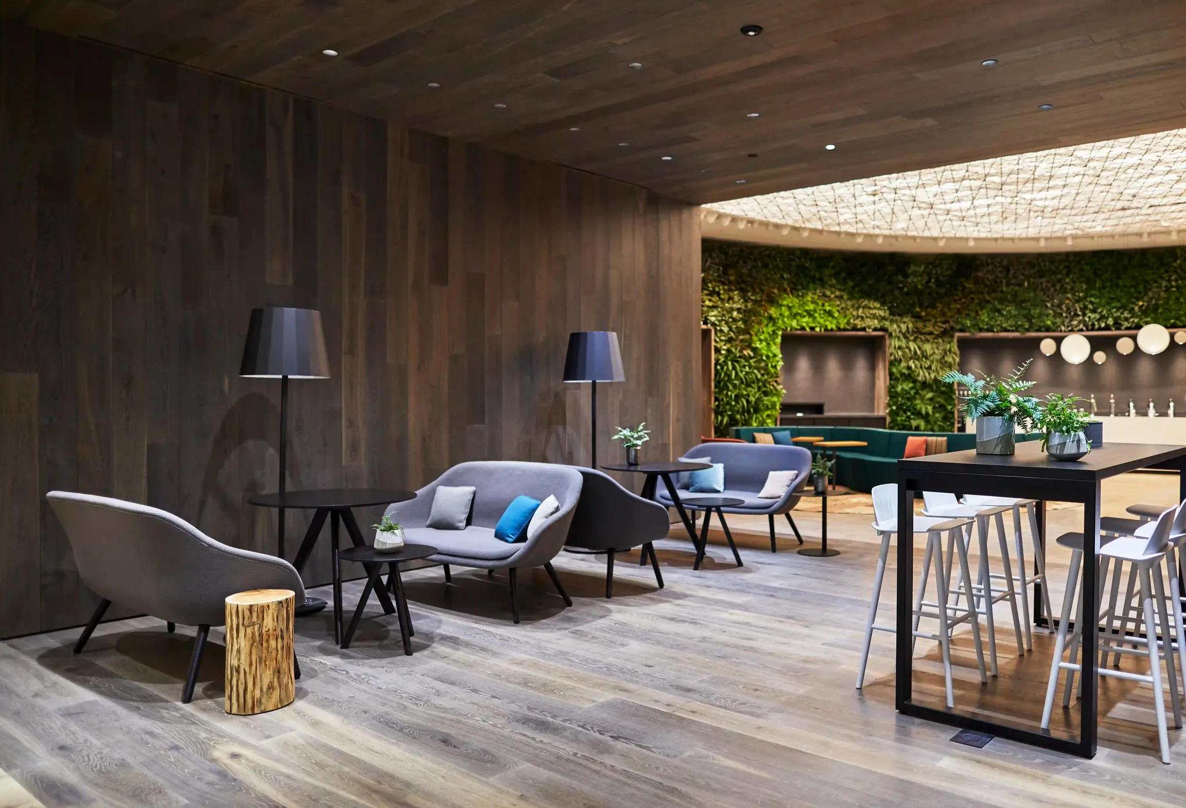 A contemporary working environment with wooden walls and a vibrant green wall.