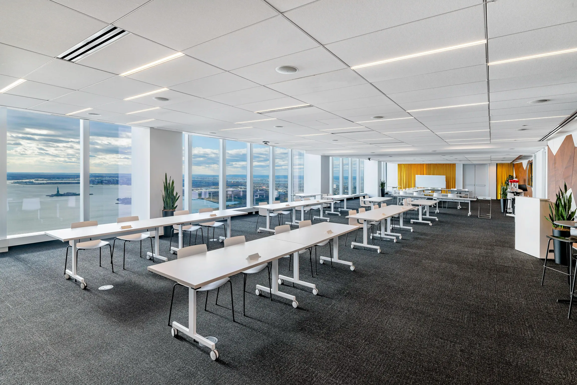 A spacious open conference or event space with rows of tables and chairs. One of Well& by Durst's offerings at One World Trade Center.