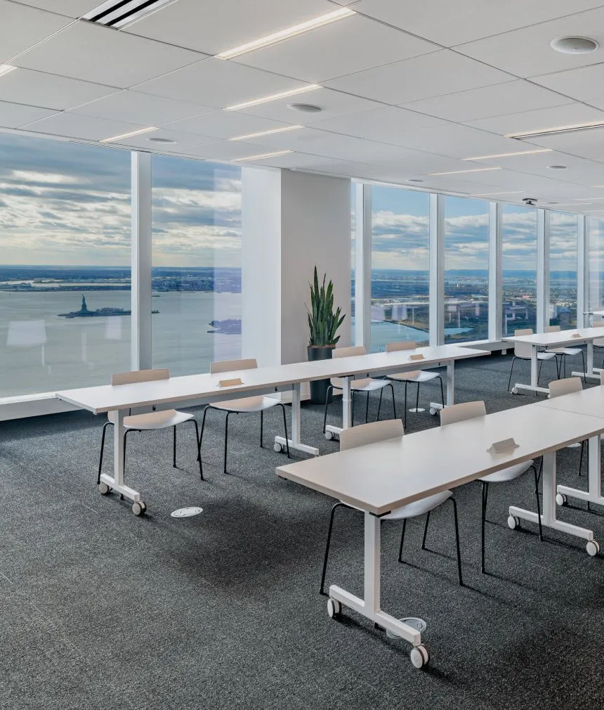 A spacious open conference or event space with rows of tables and chairs. One of Well& by Durst's offerings at One World Trade Center.