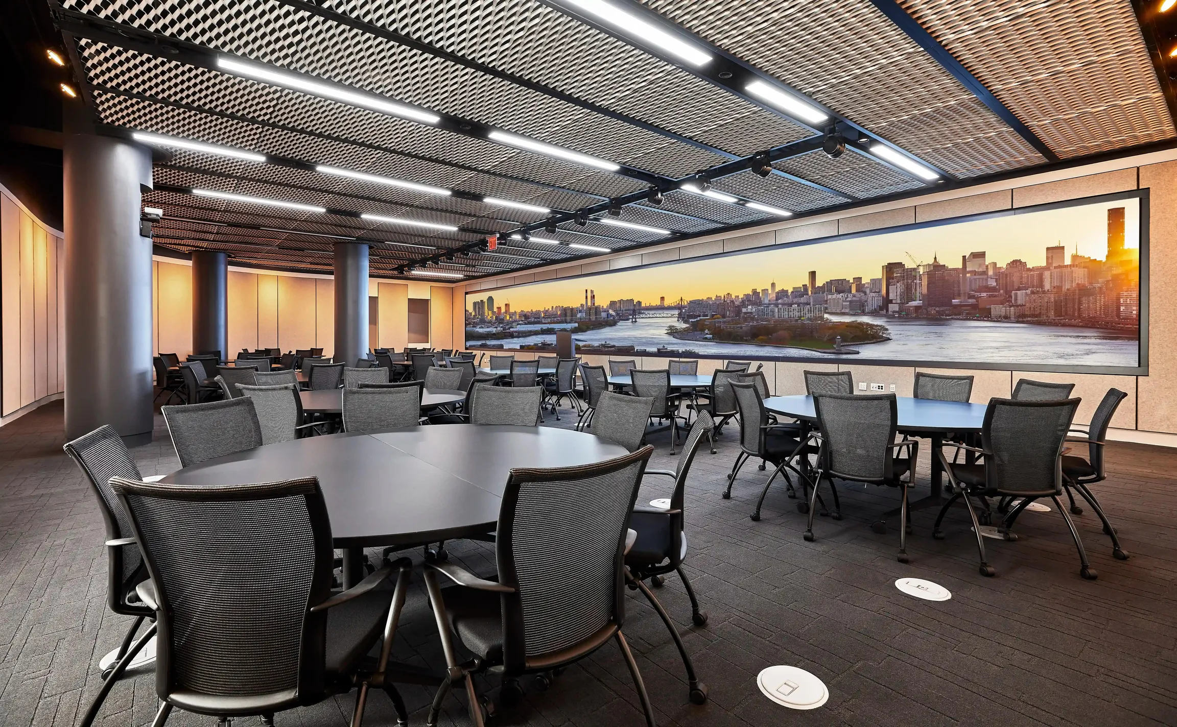 151 West 42nd conference space filled with empty chairs and a large screen that extends the far end of a wall. It displays the "Well& by Durst" logo on it.
