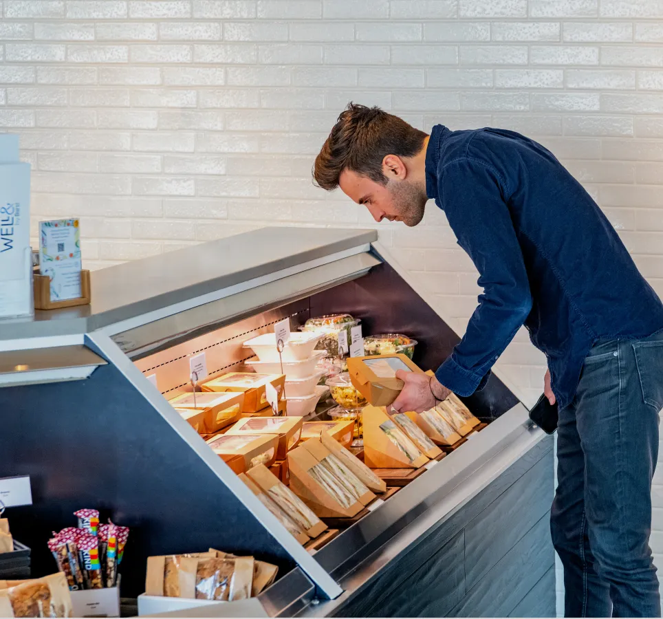 A man checking out different food options on display in a store.