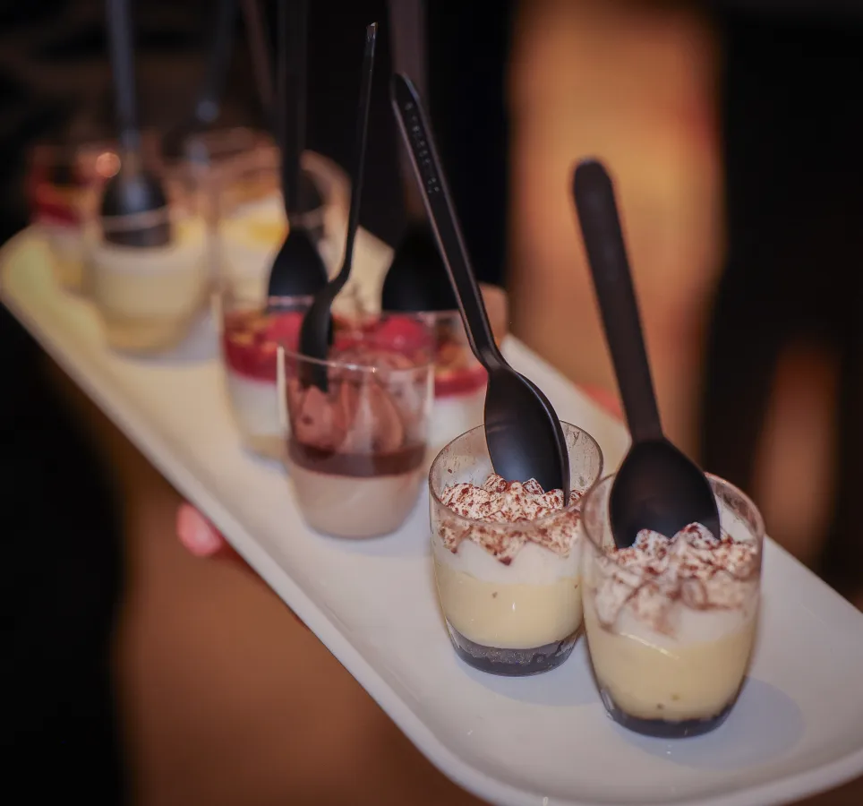 A person holding a tray of assorted desserts.