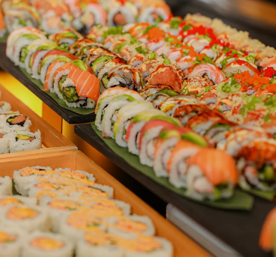 Assorted sushi rolls on a white plate, including salmon, tuna, and avocado rolls.