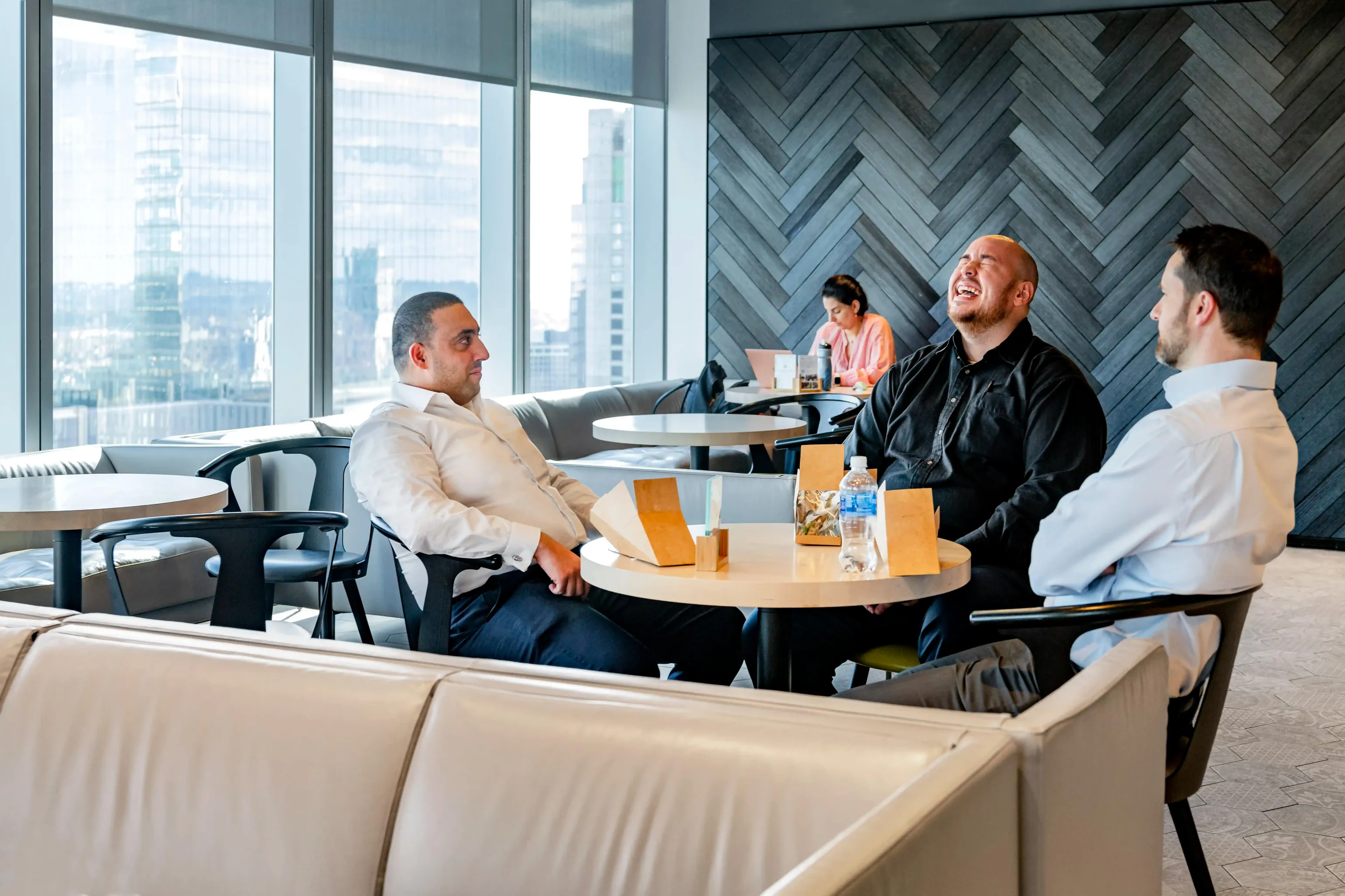 Several people sitting at a table in a cafe area that overlooks the city.