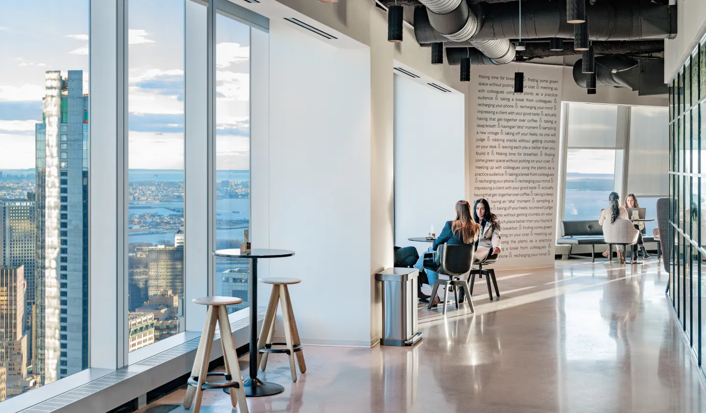 Two people sitting at a table near a large window, enjoying the city view outside.