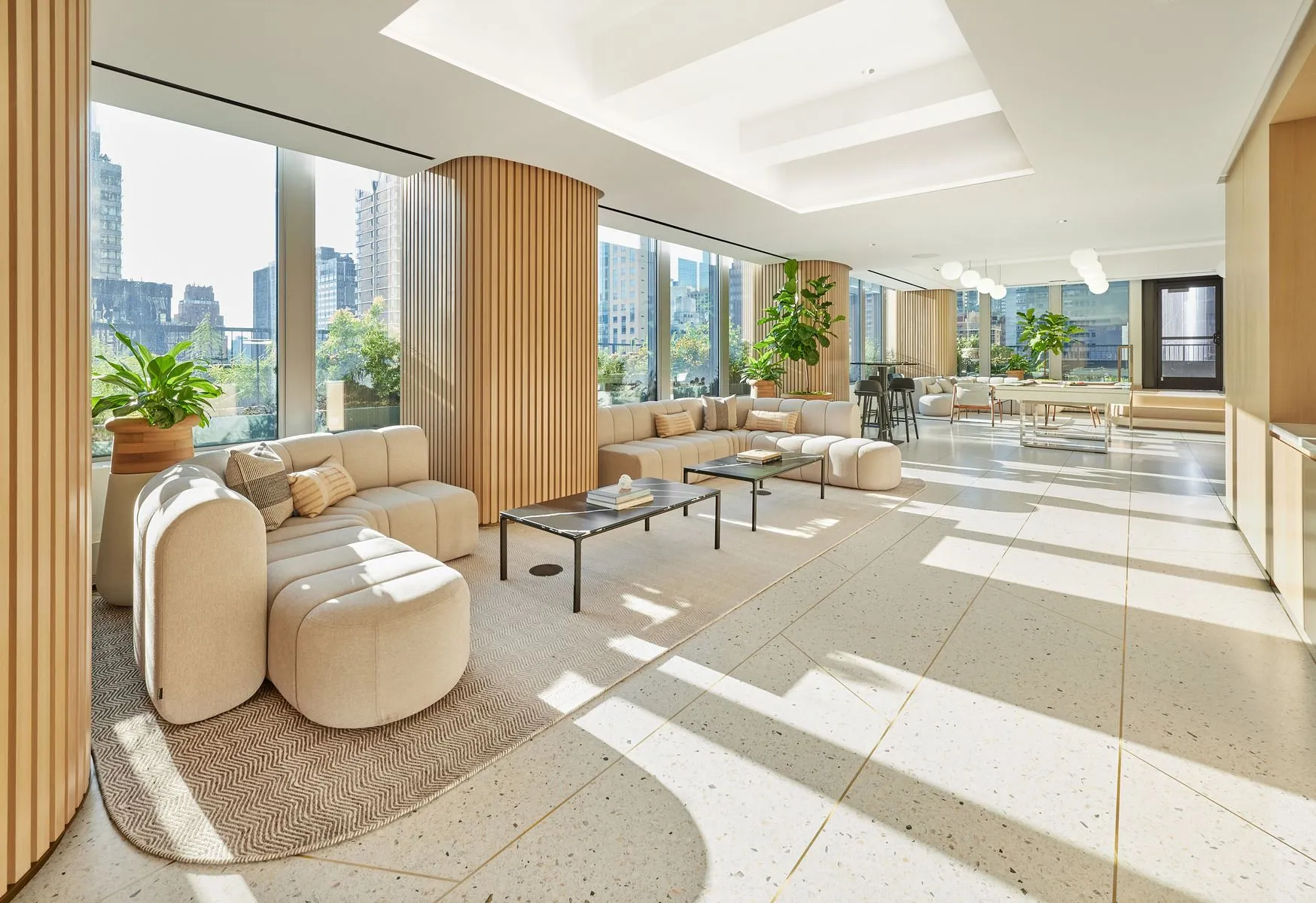 12th Floor of 825 Third Ave. Sleek amentiy lounge with floor-to-ceiling windows framing a city skyline and modern furniture.